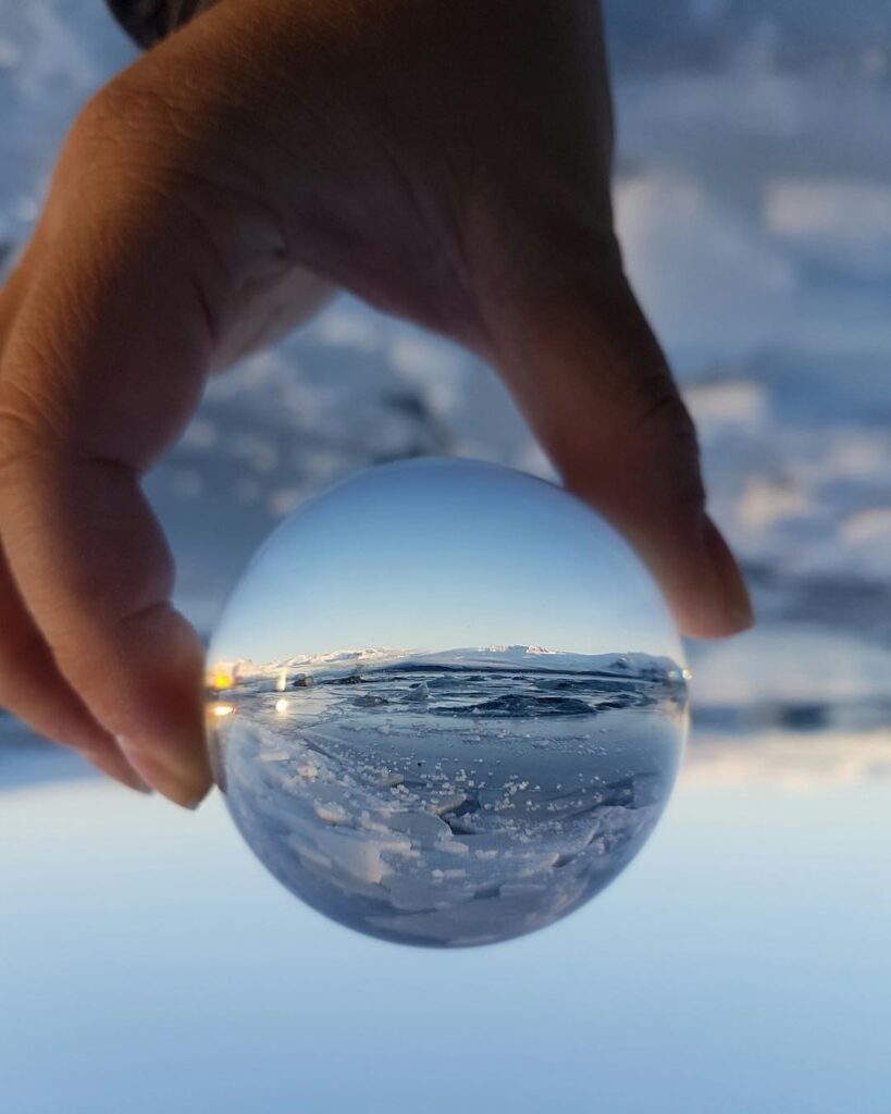 Image of a hand holding a ball with ice and water reflected in the ball