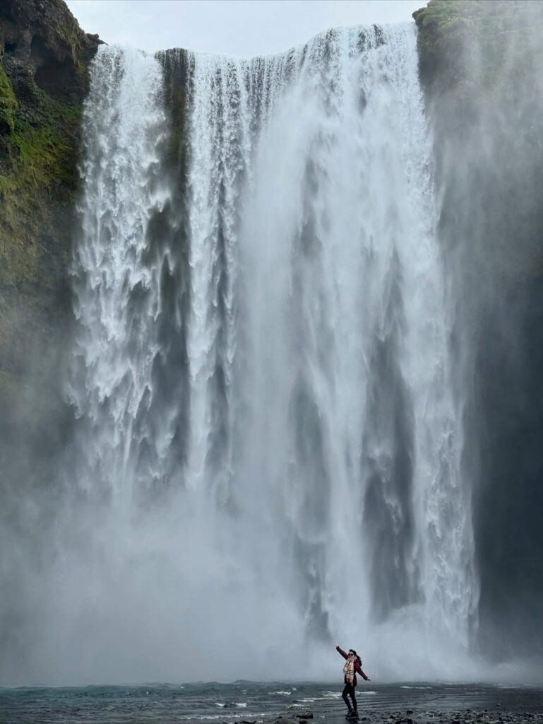 Image of a woman posing at the bottom of a waterfall