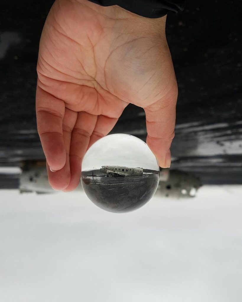 Image of a hand holding a ball with an airplane reflected in the ball
